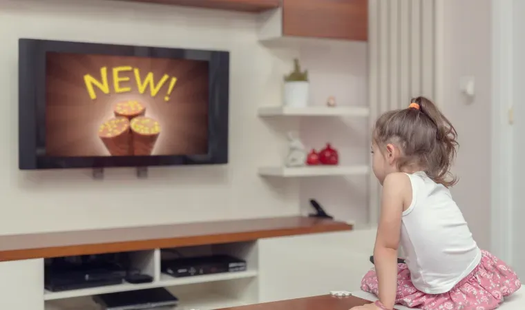 Imagem de uma criança assistindo a um programa em uma TV pequena.