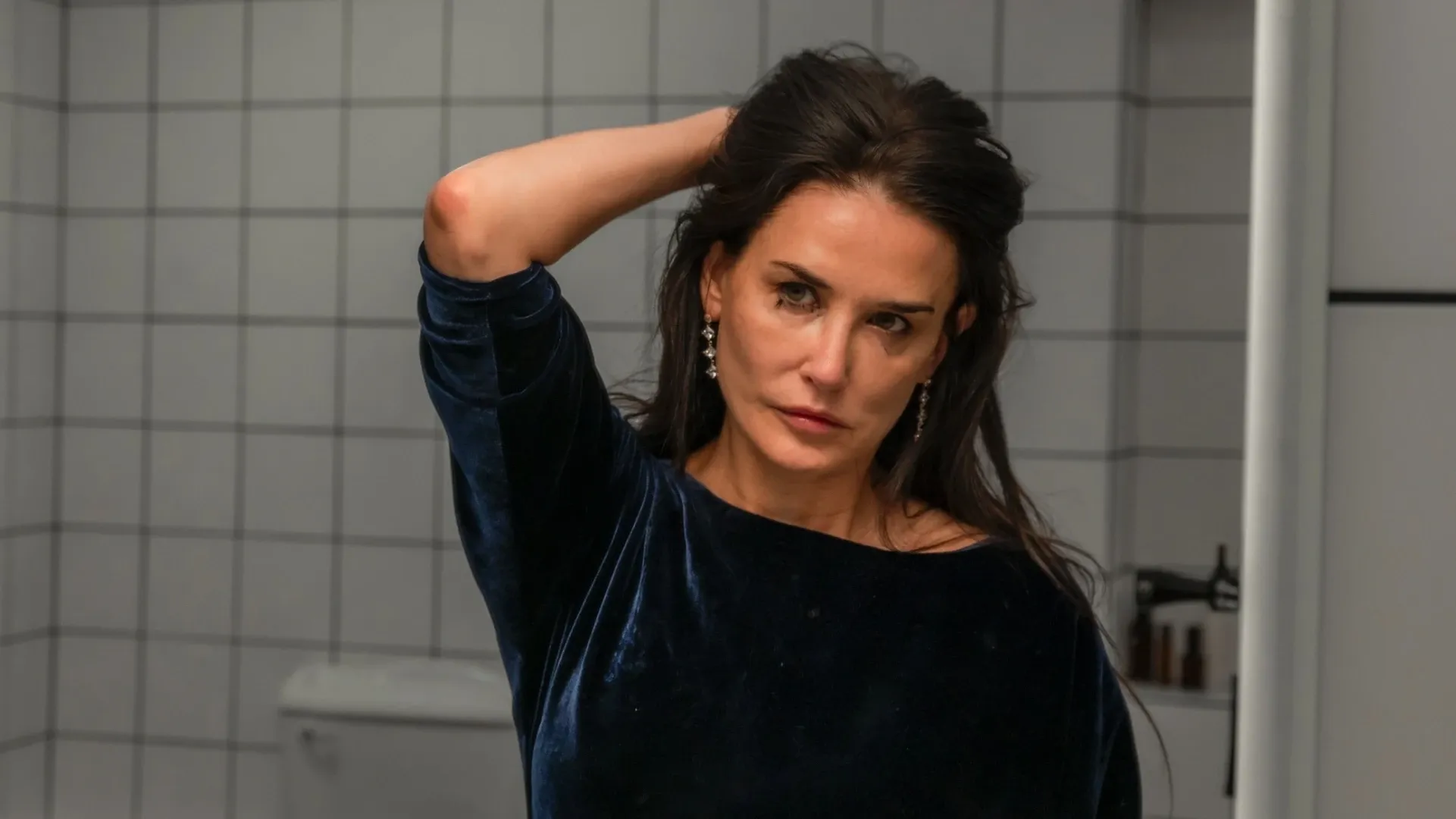 Personagem de Demi Moore se olhando no espelho