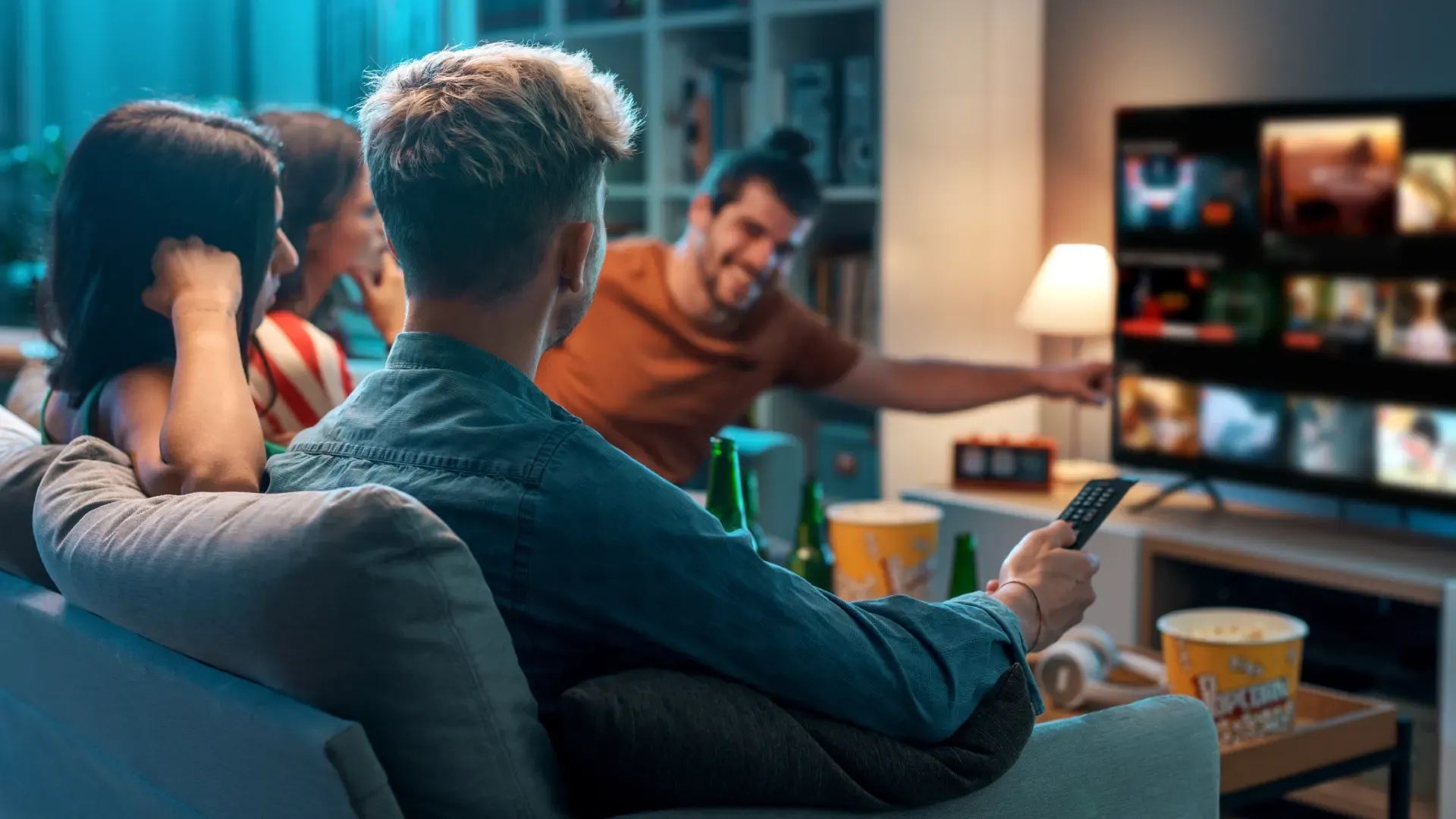 Amigos assistindo TV juntos, enquanto comem pipoca e comem cerveja