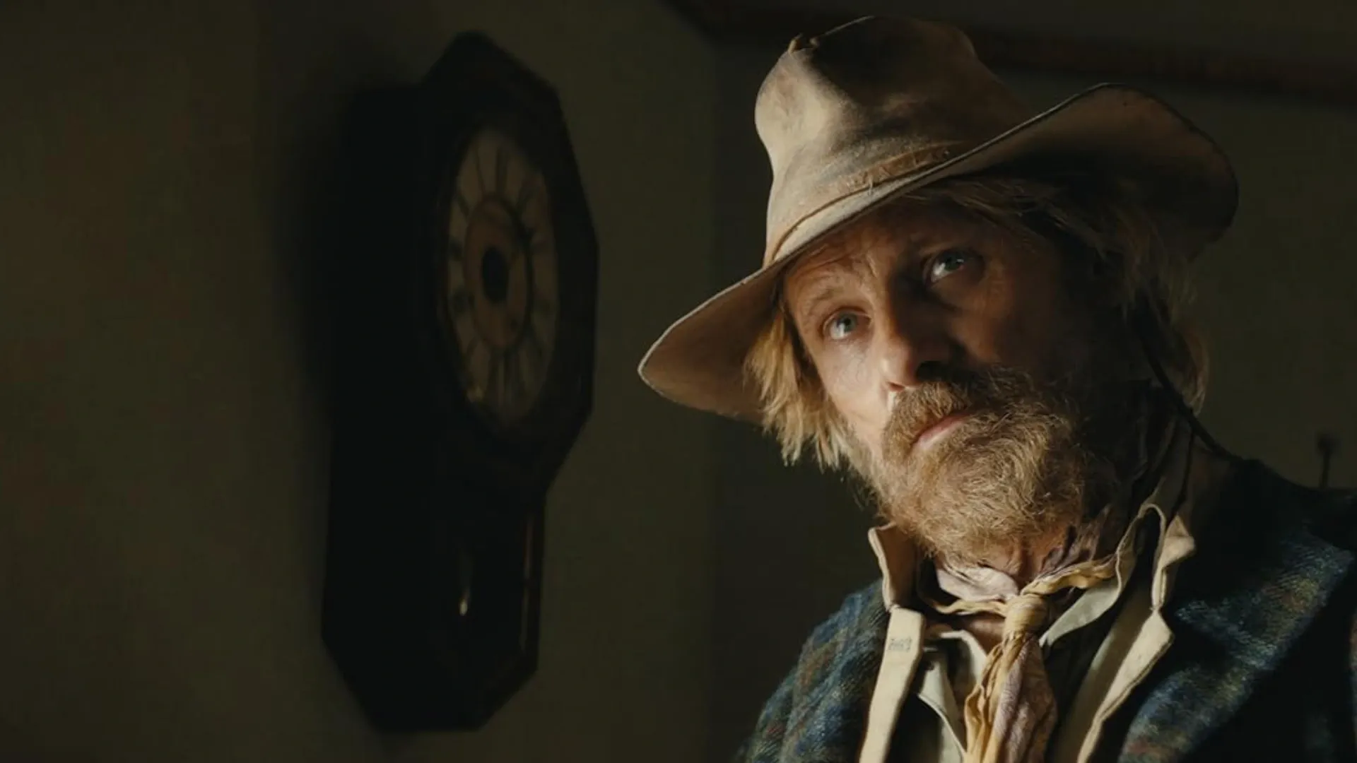 Homem cowboy barbudo enquanto encara algo sério  