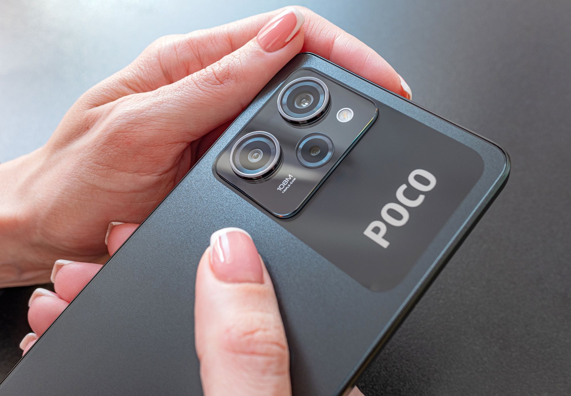 Melhor celular Poco de 2025 na mão de uma mulher em fundo preto 