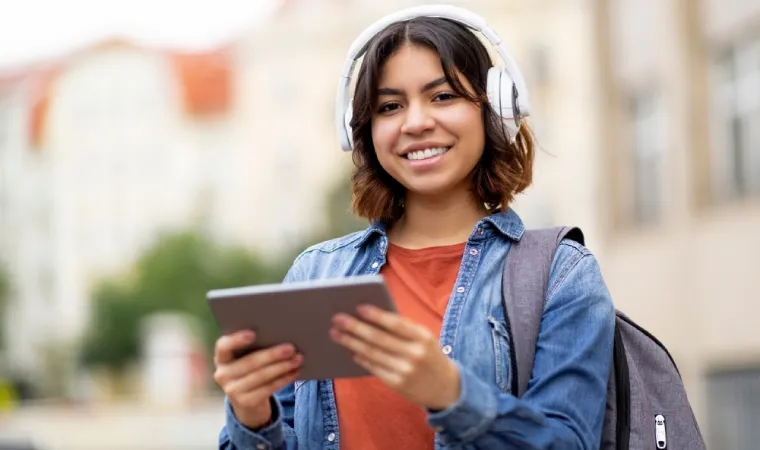 Mulher de mochila segurando um tablet para estudo em fundo desfocado