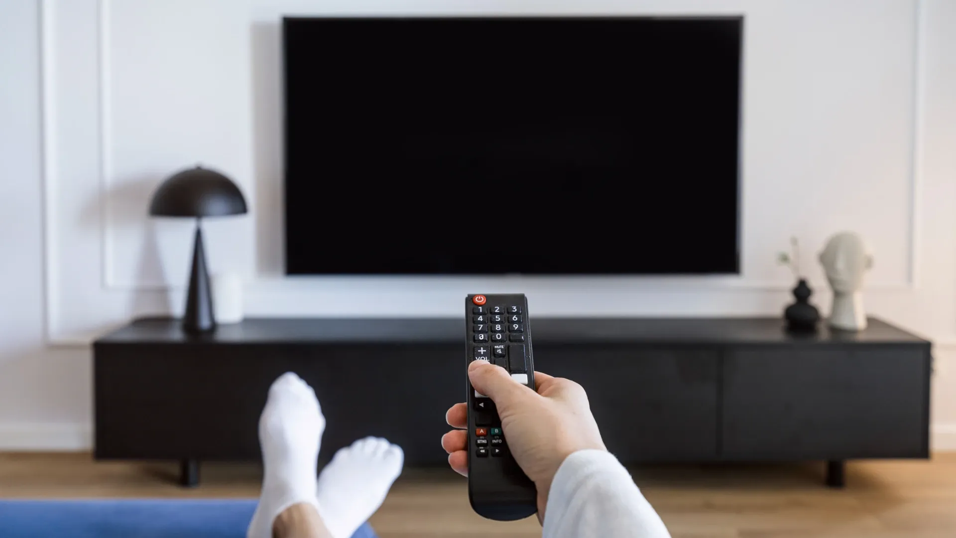 Uma pessoa está segurando um controle remoto enquanto o aponta para uma tv