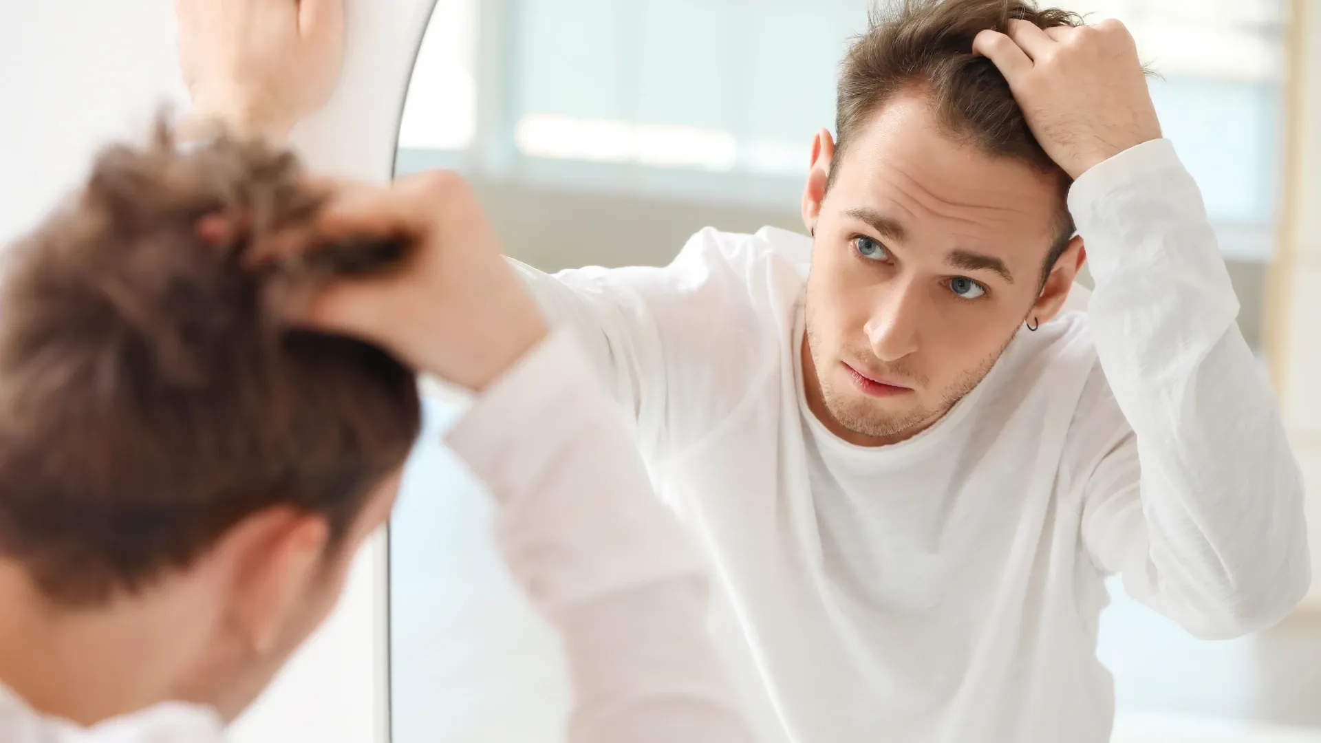 Imagem de um homem se olhando no espelho com aparência preocupada