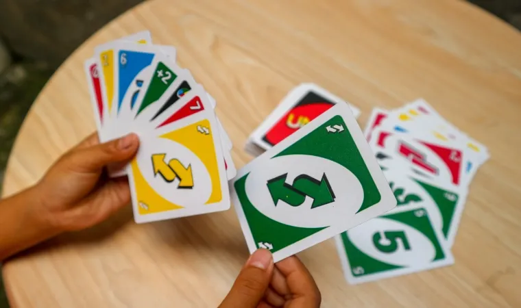 Pessoa em mesa de madeira jogando o jogo Uno