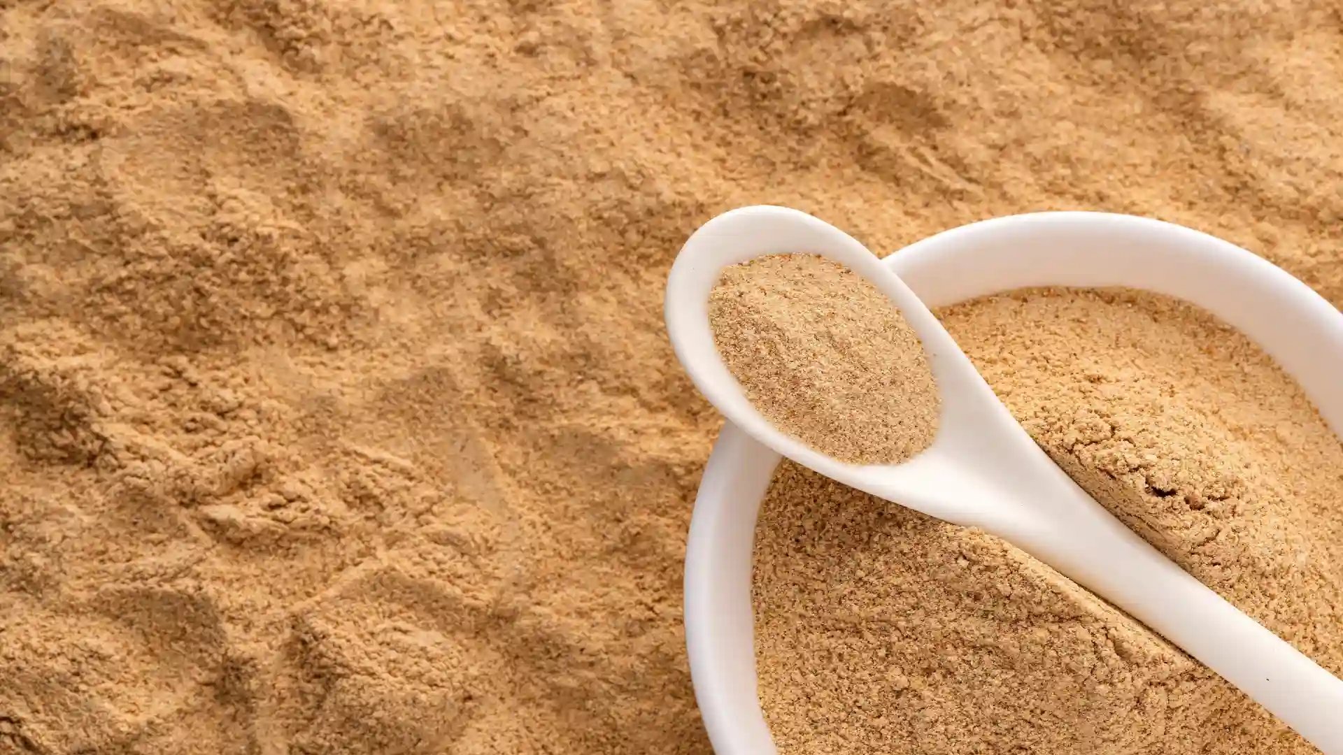  Pó de maca peruana no fundo e dentro de um pote com uma colher