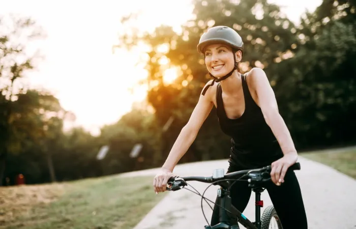 Mulher sorridente andando de bicicleta em um parque