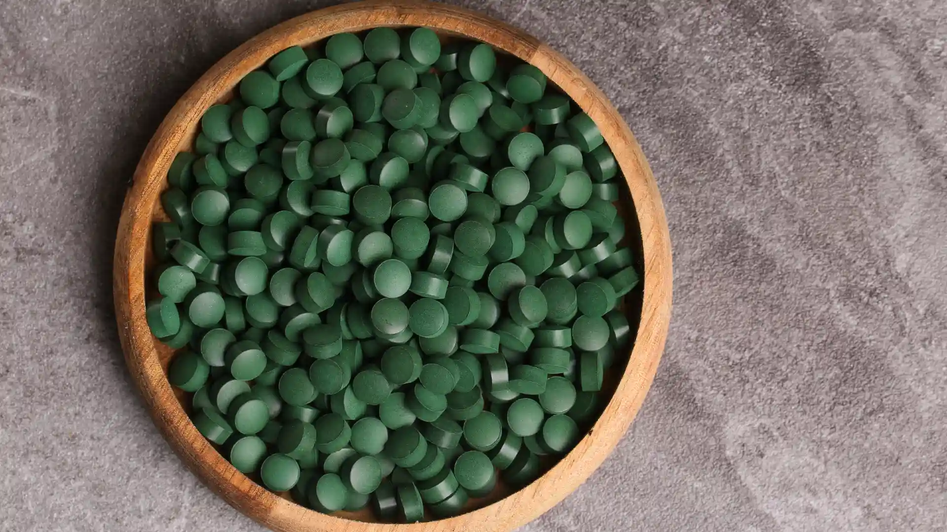 Cápsulas de spirulina em um pote de madeira