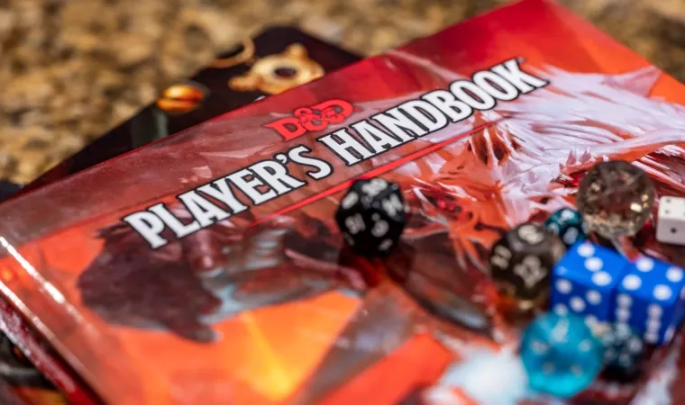 Imagem do livro do jogador de D&D com alguns dados em cima.