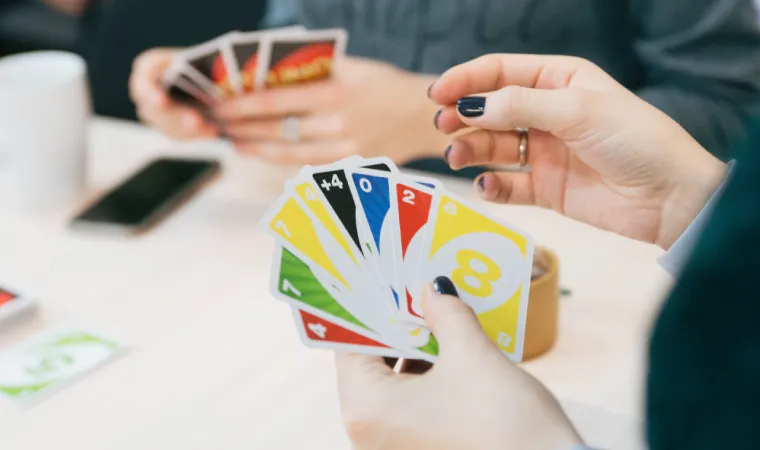  Uma pessoa segurando um baralho de UNO para selecionar uma carta. 