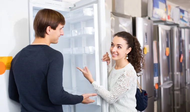 Casal olhando modelos de geladeira em seção de loja