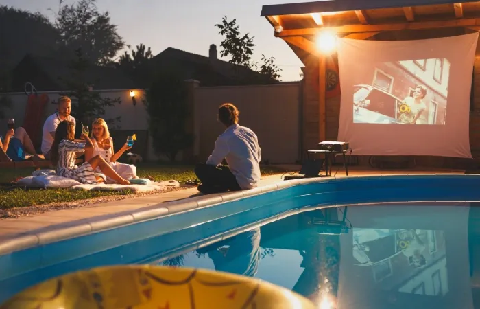 Pessoas assistindo a um filme em um projetor portátil ideal para sessões de cinema ao ar livre 