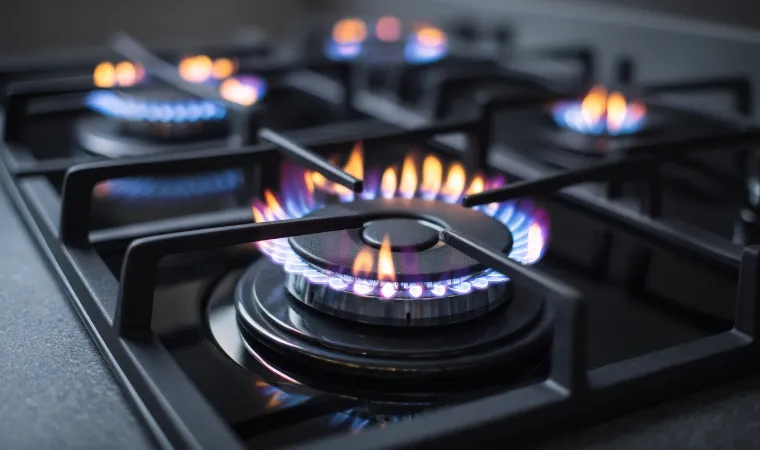 Fogão cooktop preto aceso em bancada de cozinha.