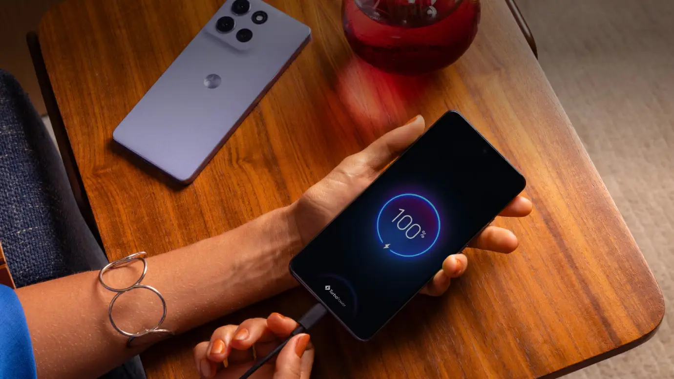 Um celular está sobre uma mão feminina com um cabo carregador plugado nele