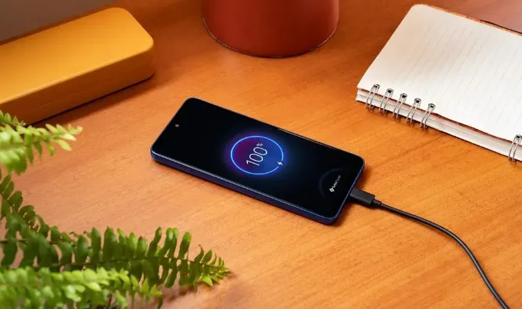 Um celular está com o carregador sobre uma mesa