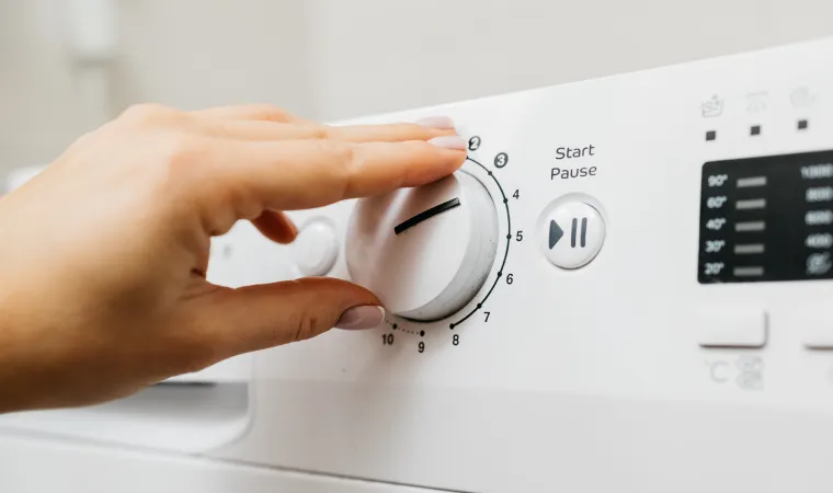 Mão ajustando a máquina de lavar e secar