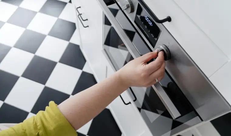 Imagem de uma mão fazendo o ajuste de aquecimento de um forno elétrico 