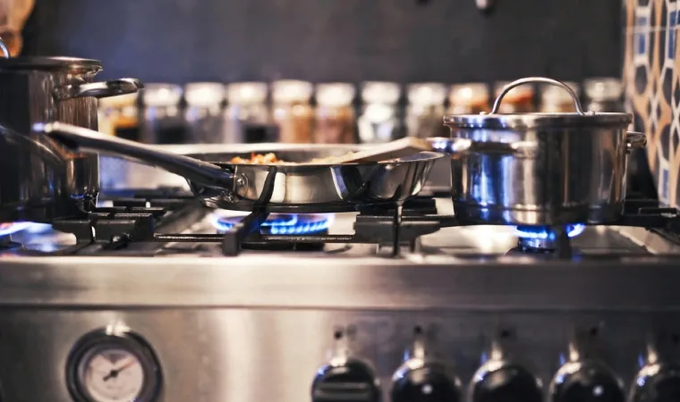  Fogão com o fogo ligado e algumas panelas em cima das chamas.