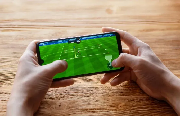 Imagem de uma pessoa jogando um jogo de futebol no celular