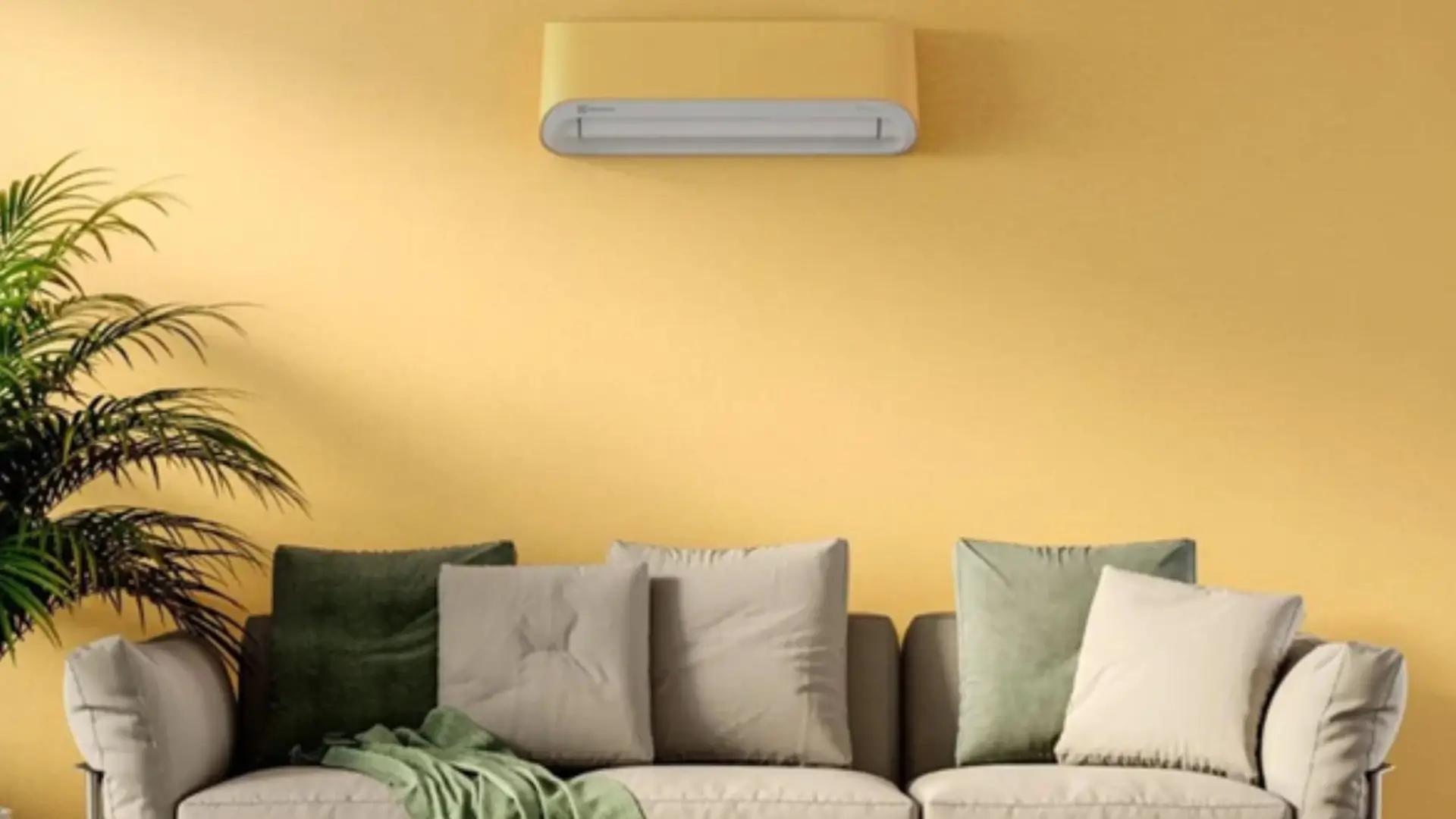 Imagem do ar-condicionado Electrolux Color Adapt amarelo instalado em sala de estar, acima de um sofá com almofadas