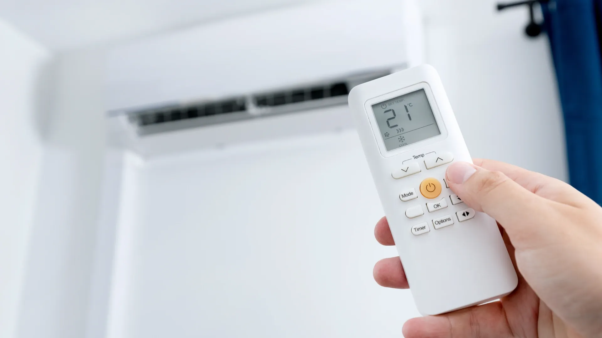 Imagem de uma pessoa com a mão levantada no rumo do ar-condicionado para checar a temperatura