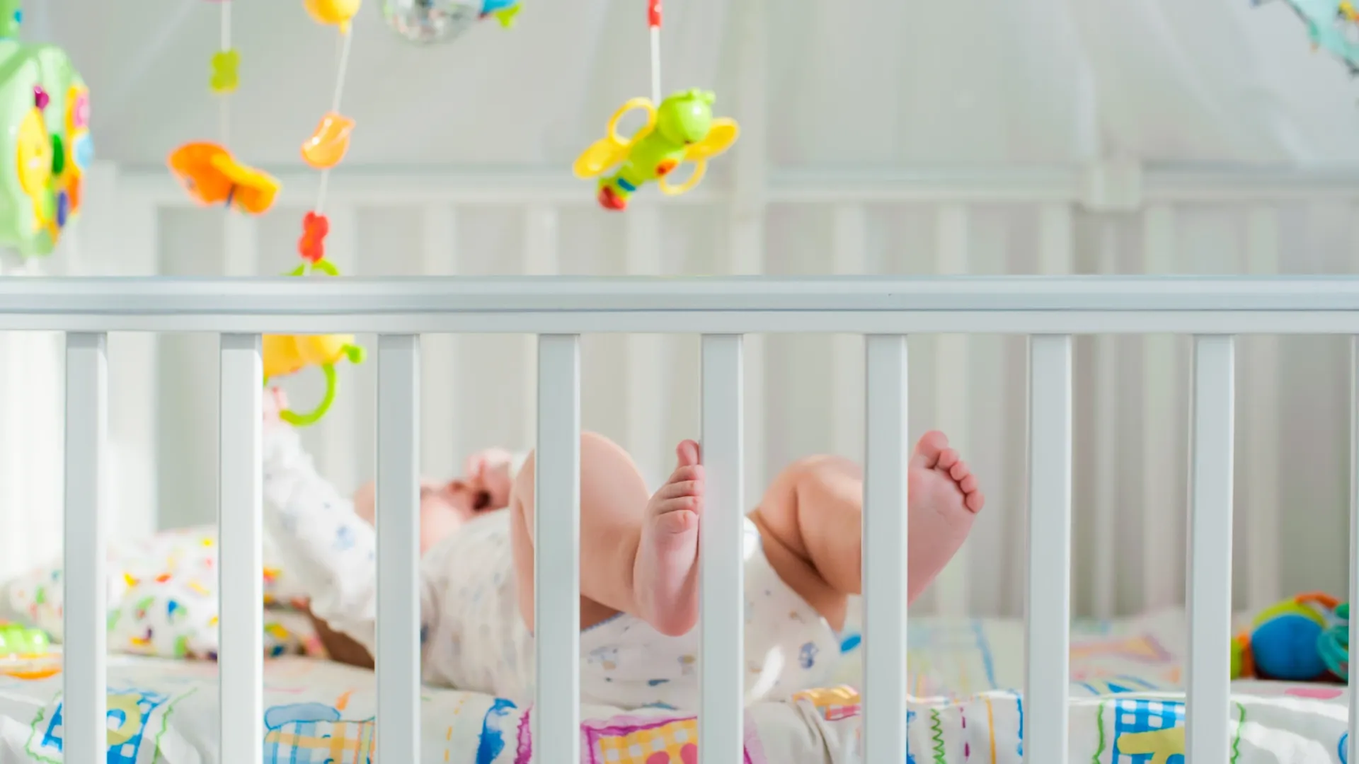 Imagem de um bebê brincando em seu berço