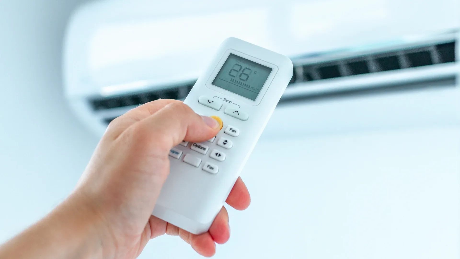 mão segurando controle remoto ajusta temperatura de ar-condicionado split