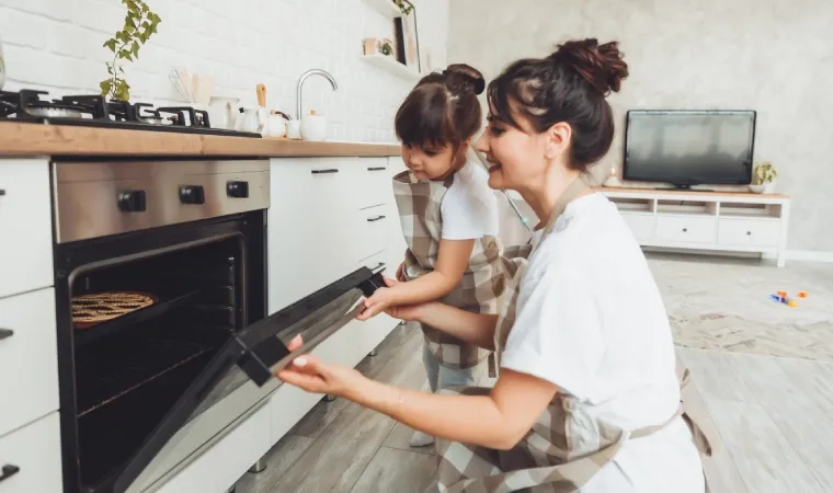 Mãe e filha abrindo o forno de um fogão Venax.