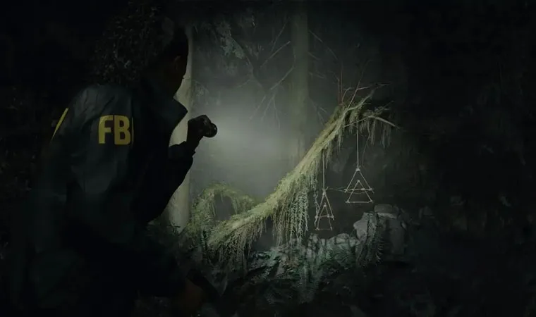 Protagonista Saga Anderson de Alan Wake 2 iluminando uma floresta à noite com gravetos pendurados em uma árvore 