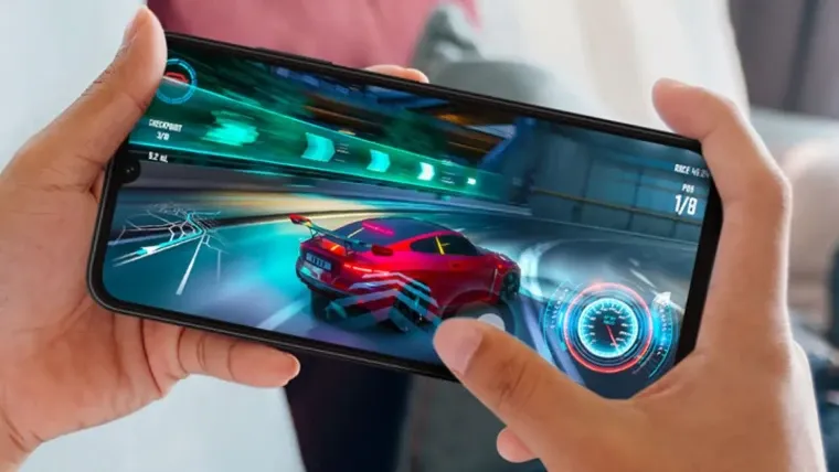 Uma pessoa segura um celular na diagonal. Na tela aparece um jogo de corrida