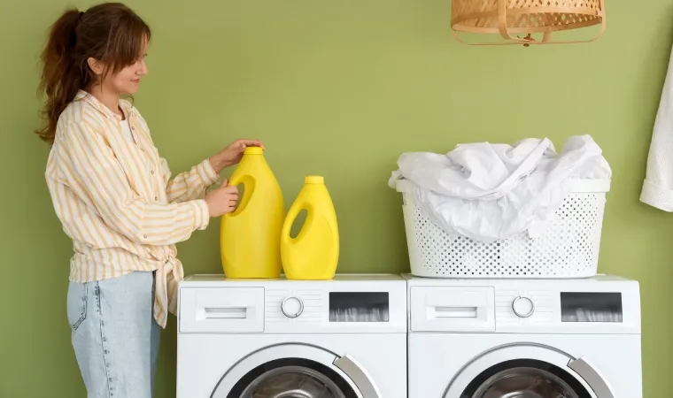 Lavanderia com duas máquinas lava e seca ao centro e uma mulher ao lado.
