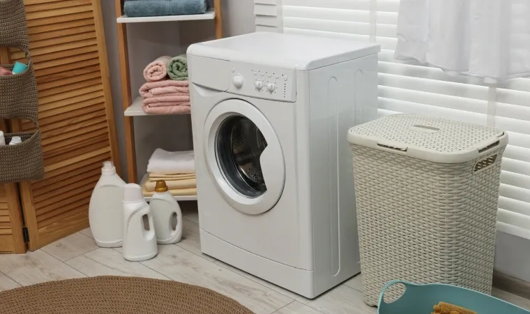 Máquina de lavar em meio a outros objetos de lavanderia.