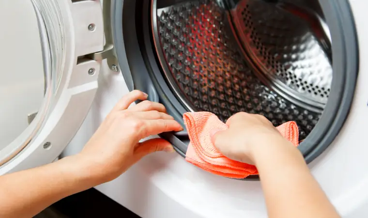 Pessoa limpando a porta de uma máquina de lavar Electrolux 15kg.