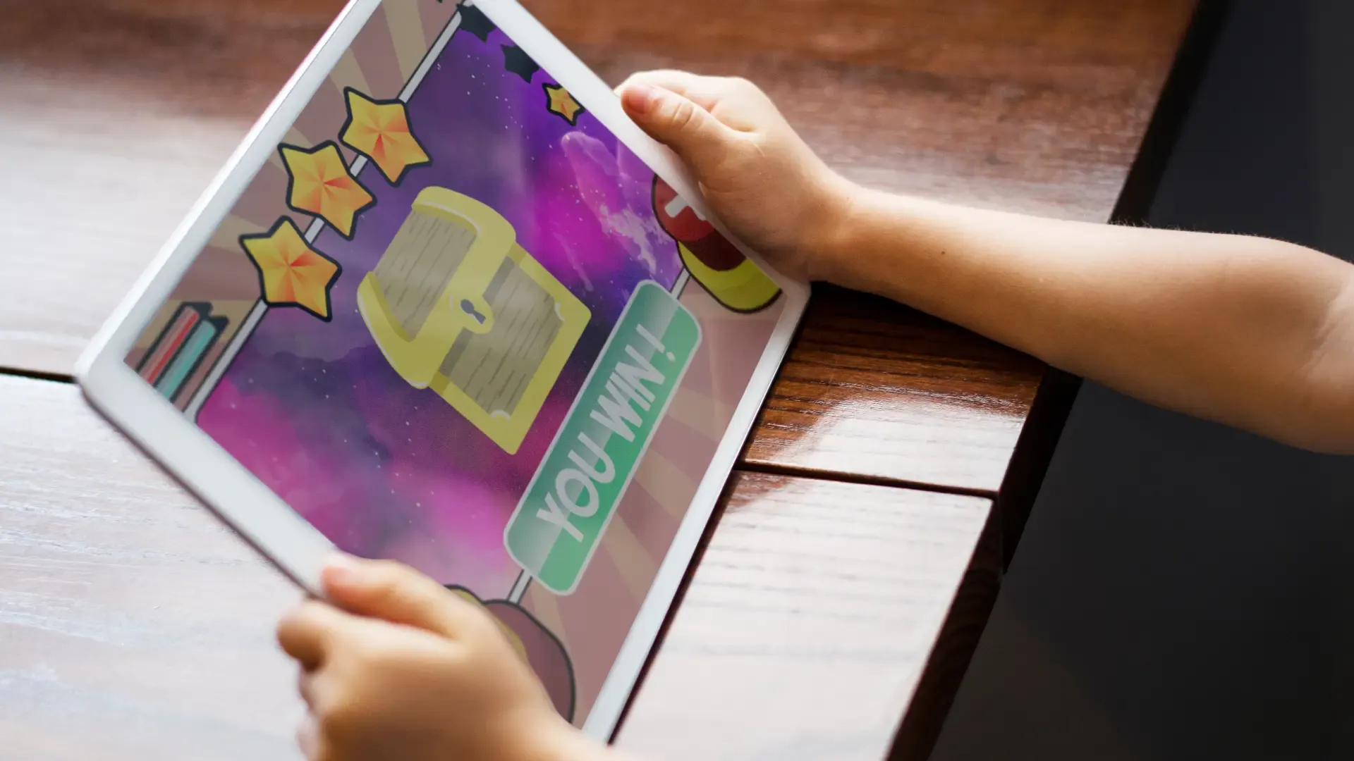 Uma criança está com um tablet na mão enquanto tem um jogo na tela