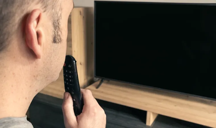 Imagem de um homem dando um comando de voz ao controle da TV