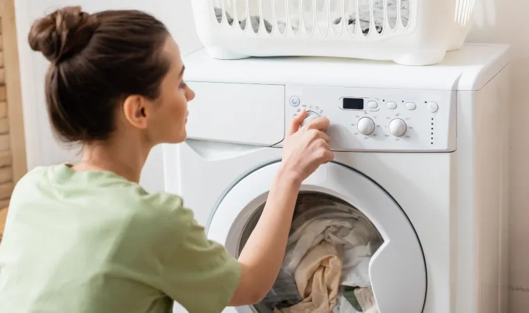 Mulher ajustando funções de uma máquina de lavar roupa.