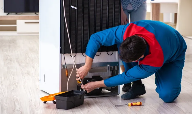 Técnico consertando o moto da geladeira.