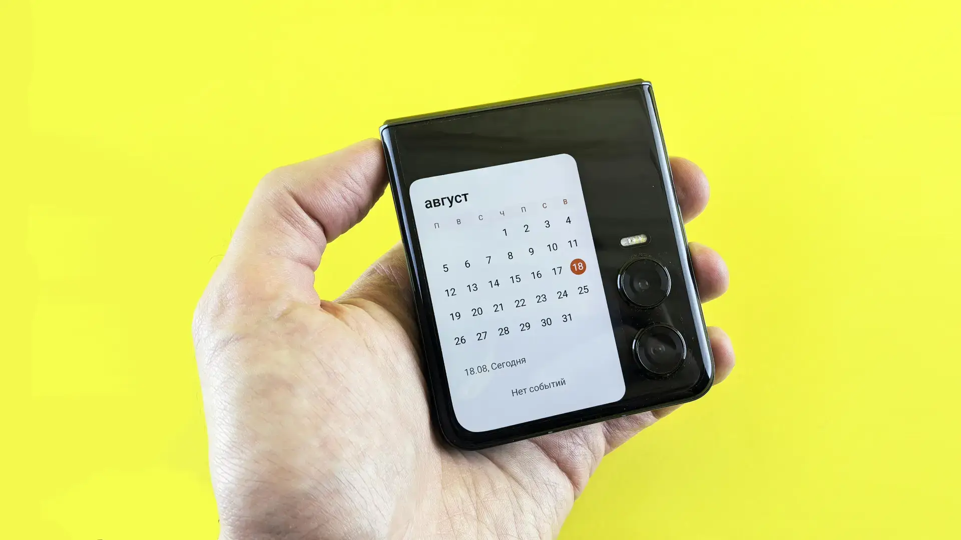 Uma pessoa mostra um celular dobrável fechado, com o calendário na tela