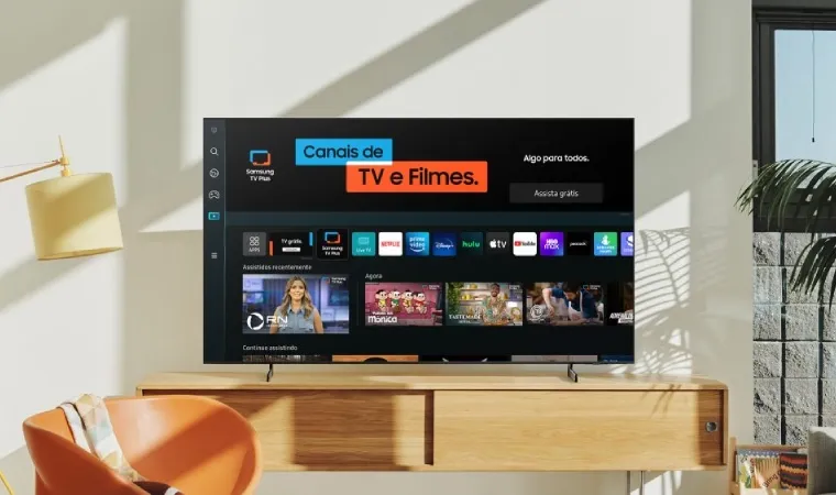 Imagem mostra uma sala contendo TV da Samsung apresentando a tela inicial do serviço Samsung TV Plus