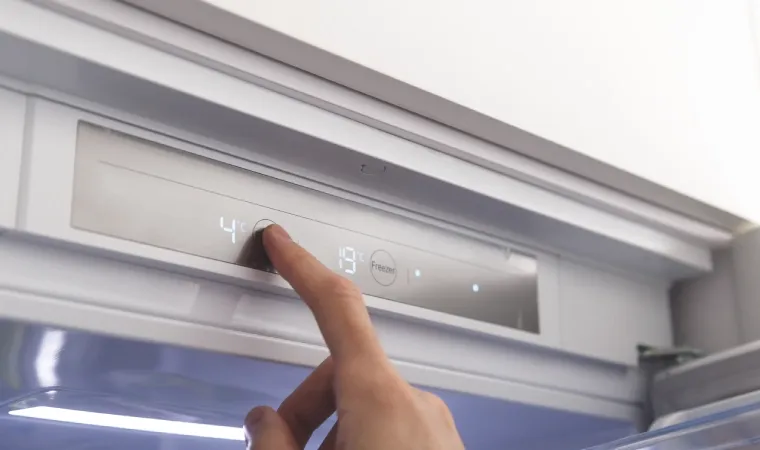  Mão masculina mexendo em painel digital da geladeira.