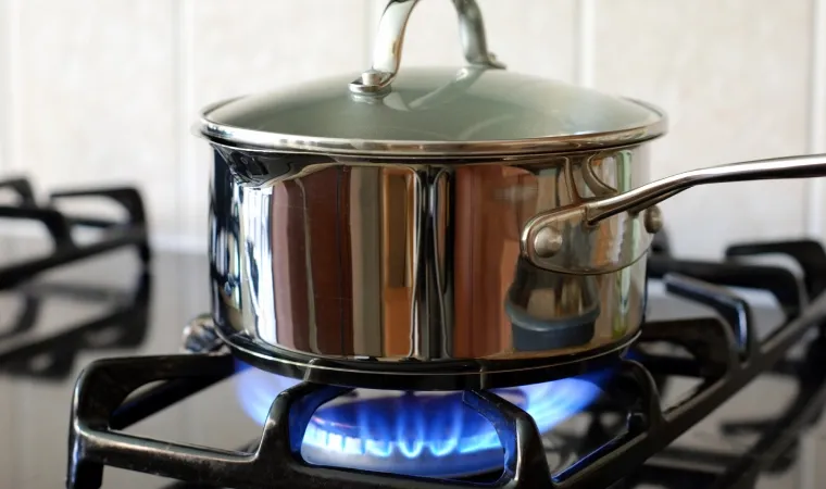 Panela de inox em um fogão Esmaltec com chama acesa.