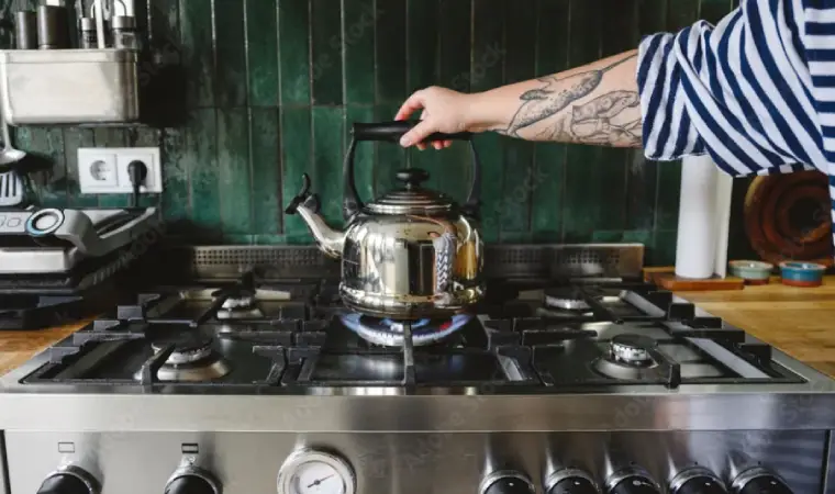 mulher com o braço tatuado esquentando água no fogão 6 bocas