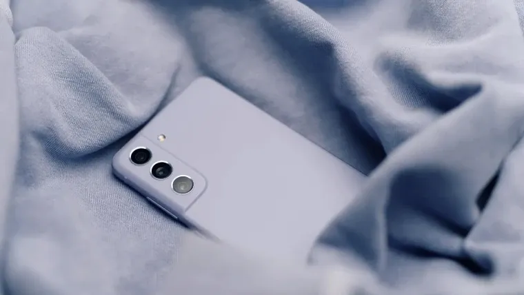 Traseira do celular Galaxy S21 FE lilas em cima de uma tolha lilás amassada