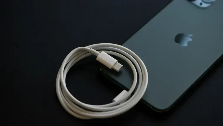 Um celular está deitado com a tela virada para baixo com o cabo lightning sobre ele