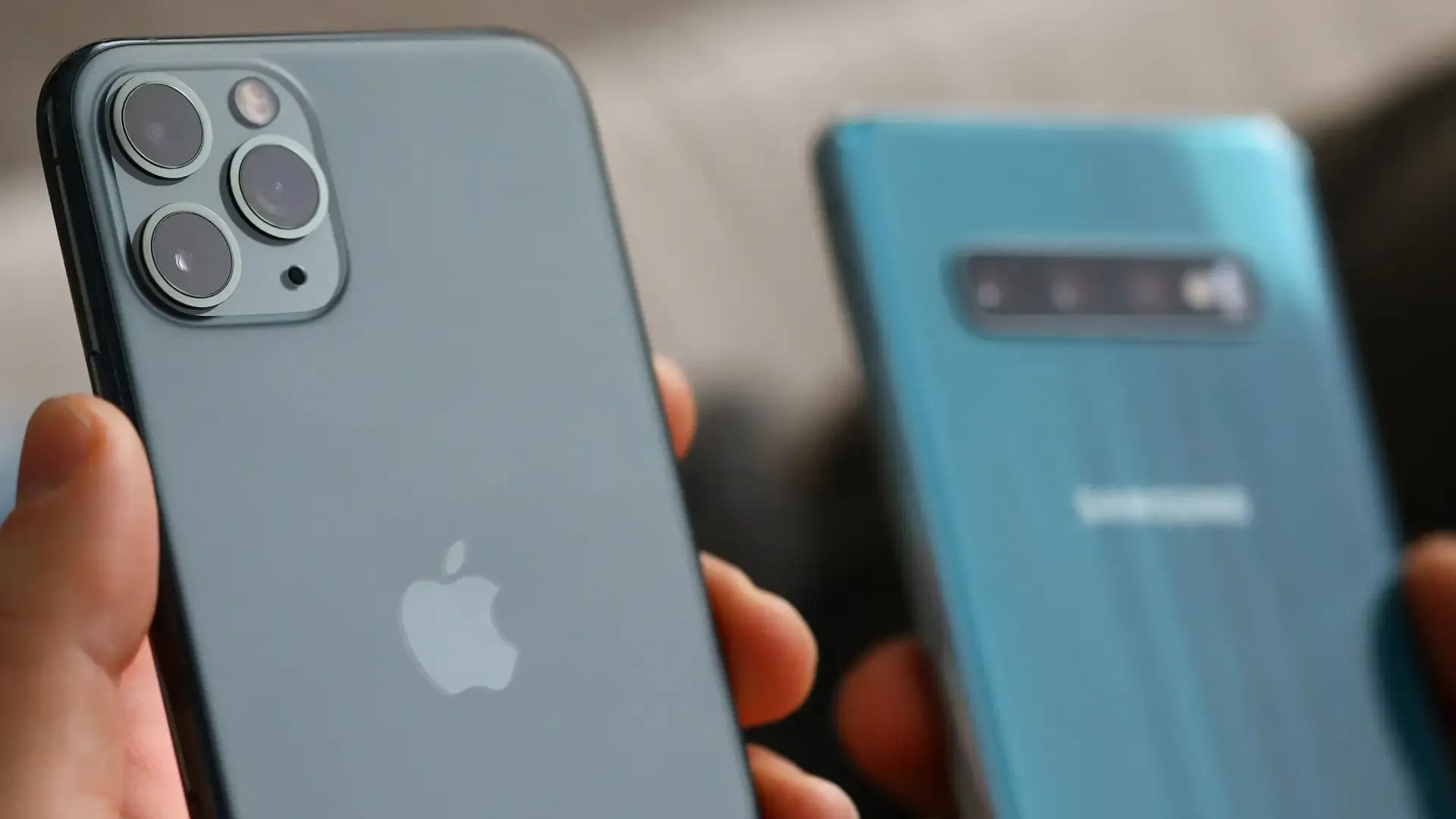 Um celular da Apple e outro da Samsung estão lado a lado, apenas com as câmeras sendo mostradas