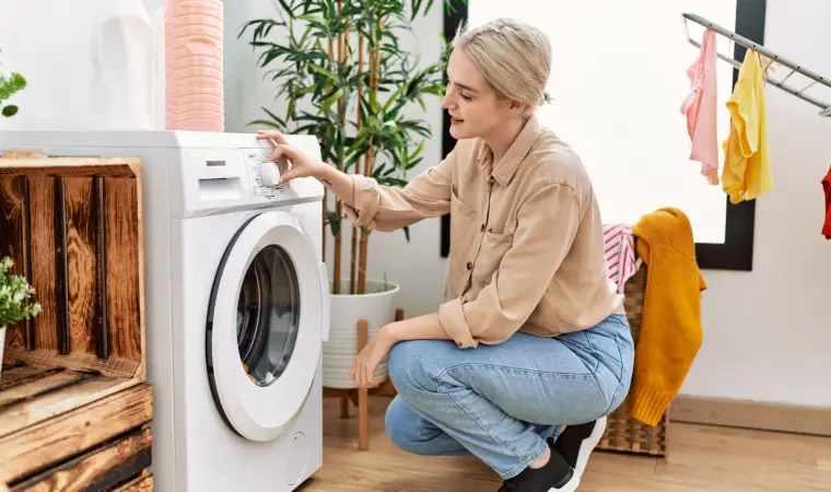 Pessoa agachada configurando uma máquina de lavar 11kg.