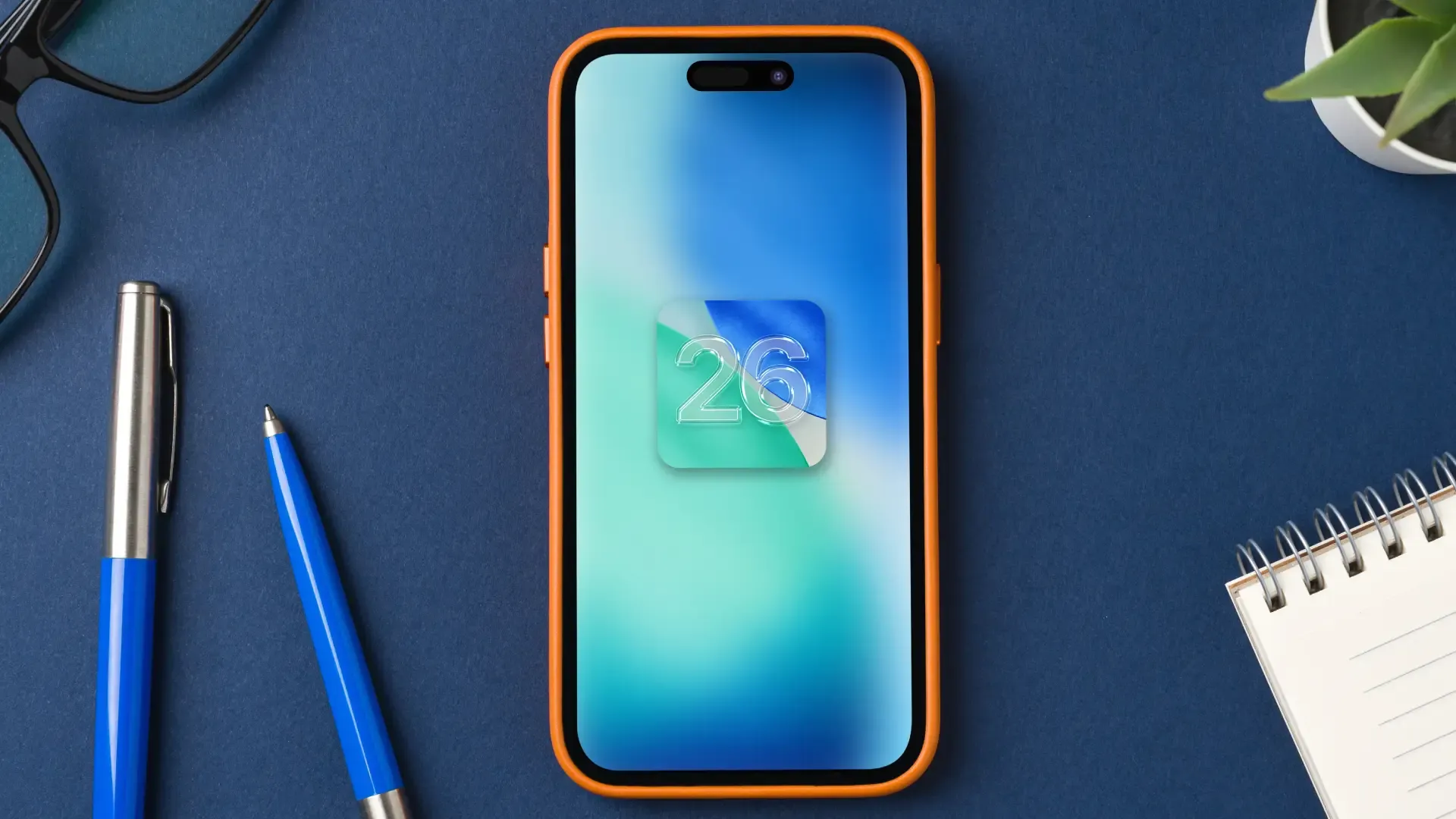 Um telefone está sobre uma mesa. Na tela, que está ligada, aparece o ícone do iOS 26 