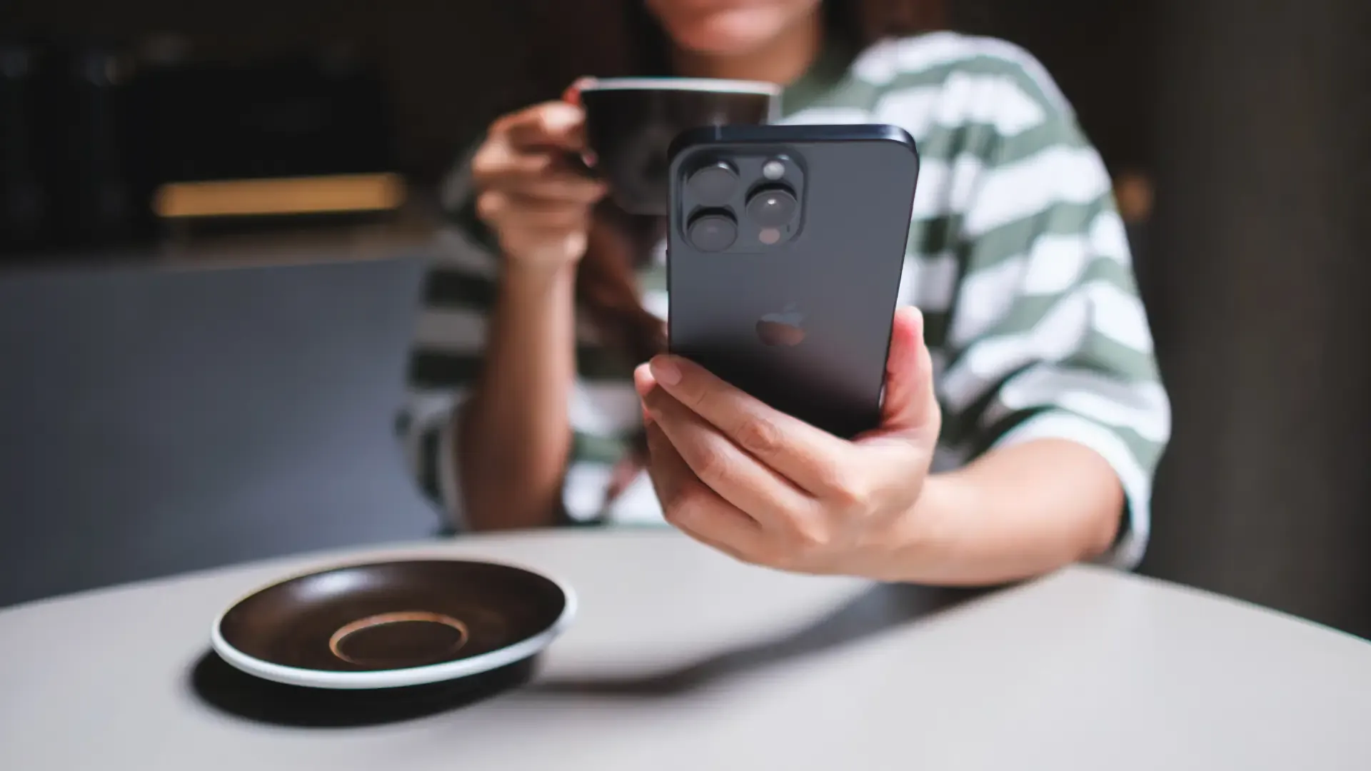 Uma pessoa está com uma xícara na mão e na outra está segurando um celular