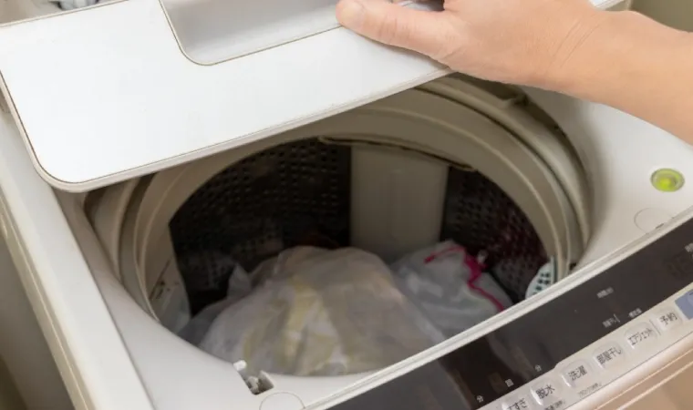 Tanquinho de lavar aberto com roupas dentro.