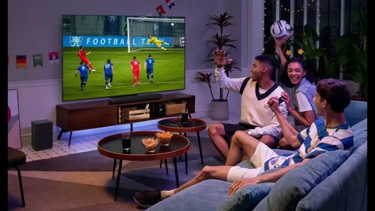Trio de amigos assistindo um jogo de futebol na TV TCL C755 em uma sala de estar